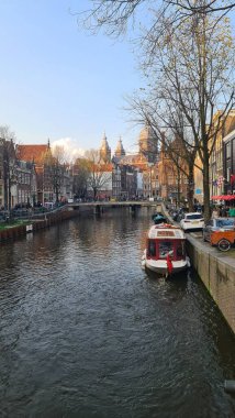 Amsterdam, Hollanda - 22 Nisan 2023: İlkbahar günlerinde Amsterdam 'ı keşfetmek. Amstel nehri etrafında bisiklet sürmek, eski evler ve şehrin eski kısmının güzel manzarası..
