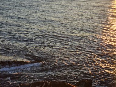 Cenova Nervi, İtalya - 23 Kasım 2023: Kışın denizin üzerinde güzel bir gün batımı. Turuncu ve kırmızı gökyüzü suyun üzerine yansıdı. Açık mavi gökyüzü manzarası.