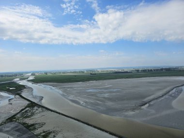 Mont Saint Michel, Fransa - 20 Mayıs 2024: Baharda Saint Michel Normandiya 'dan güzel manzara. Gökyüzü renkleri suya yansıdı. İlk güneşli günlerinde yeşil arazi.