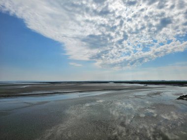 Mont Saint Michel, Fransa - 20 Mayıs 2024: Baharda Saint Michel Normandiya 'dan güzel manzara. Gökyüzü renkleri suya yansıdı. İlk güneşli günlerinde yeşil arazi.