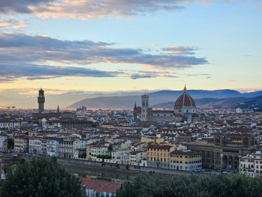 Floransa, İtalya - 5 Ekim 2024: Piazzale Michelangelo 'dan altın gün batımında Floransa' nın nefes kesici manzarası. Duomo, Vecchio Sarayı ve diğer Rönesans simgeleri sıcak akşam günbatımında güneşlenirler.