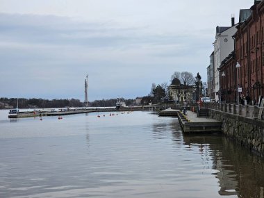 Finlandiya, Helsinki - 11 Mart 2025: Helsinki şehrini kış günlerinde keşfetmek. Şehrin eski limanını geziyorum. Bulutlu gökyüzü Kuzey Denizi 'ne yansıyor.