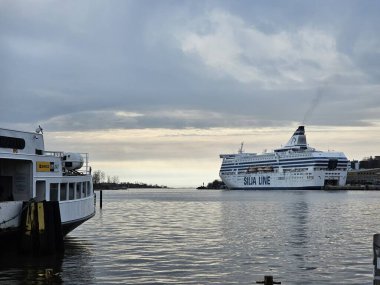 Finlandiya, Helsinki - 11 Mart 2025: Helsinki şehrini kış günlerinde keşfetmek. Şehrin eski limanını geziyorum. Bulutlu gökyüzü Kuzey Denizi 'ne yansıyor.