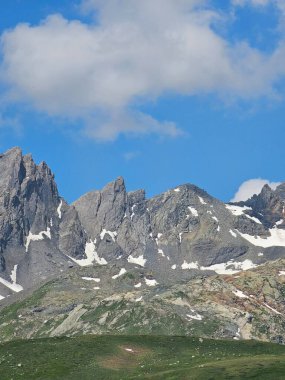 La Thuile, Val D 'Aosta, Temmuz 02 2025: Alplere panoramik manzara, küçük doğal bir göle yansıyan güzel yeşil manzara. Bulutlu güzel mavi gökyüzü. Biraz karlı dağlar. La Thuile köyünün havadan görünüşü.