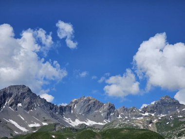 La Thuile, Val D 'Aosta, Temmuz 02 2025: Alplere panoramik manzara, küçük doğal bir göle yansıyan güzel yeşil manzara. Bulutlu güzel mavi gökyüzü. Biraz karlı dağlar. La Thuile köyünün havadan görünüşü.