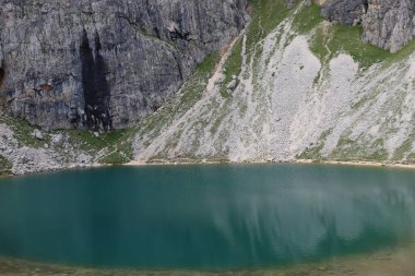 Trentino, İtalya - 29 Temmuz 2025: Piz Boe 'nun görkemli panoramik manzarası ve çevreleyen Dolomite tepeleri, yemyeşil vadiler ve açık mavi bir gökyüzü altında dağınık kar. Boe Gölü 'ne güzel bir manzara, ve su üzerinde gökyüzü yansıması..