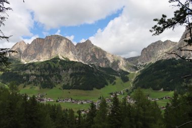 Trentino, İtalya - 29 Temmuz 2025: Piz Boe 'nun görkemli panoramik manzarası ve çevreleyen Dolomite tepeleri, yemyeşil vadiler ve açık mavi bir gökyüzü altında dağınık kar. Boe Gölü 'ne güzel bir manzara, ve su üzerinde gökyüzü yansıması..
