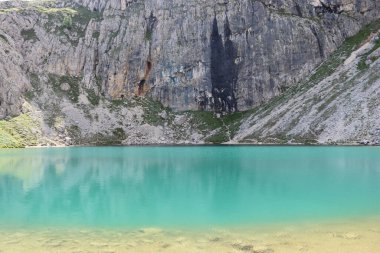 Trentino, İtalya - 29 Temmuz 2025: Piz Boe 'nun görkemli panoramik manzarası ve çevreleyen Dolomite tepeleri, yemyeşil vadiler ve açık mavi bir gökyüzü altında dağınık kar. Boe Gölü 'ne güzel bir manzara, ve su üzerinde gökyüzü yansıması..