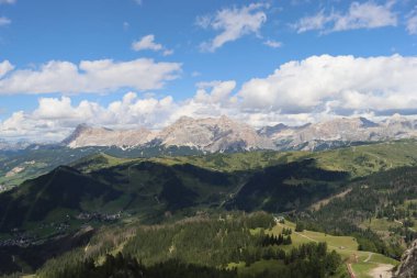 Trentino, İtalya - 29 Temmuz 2025: Piz Boe 'nun görkemli panoramik manzarası ve çevreleyen Dolomite tepeleri, yemyeşil vadiler ve açık mavi bir gökyüzü altında dağınık kar. Boe Gölü 'ne güzel bir manzara, ve su üzerinde gökyüzü yansıması..