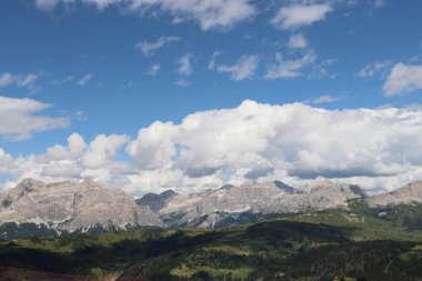 Trentino, İtalya - 29 Temmuz 2025: Piz Boe 'nun görkemli panoramik manzarası ve çevreleyen Dolomite tepeleri, yemyeşil vadiler ve açık mavi bir gökyüzü altında dağınık kar. Boe Gölü 'ne güzel bir manzara, ve su üzerinde gökyüzü yansıması..