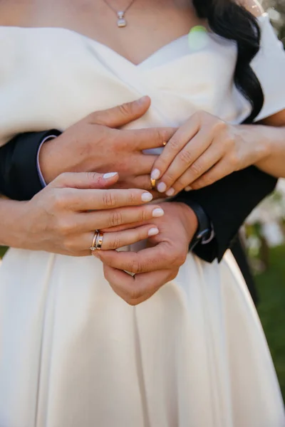 the hands of the bride and groom exchange rings in an embrace