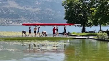 Kürek çeken kürekçiler yaz mevsiminde ioannina ağaçlarının altında Pamvotis Gölü 'nde antrenman yapıyorlar.