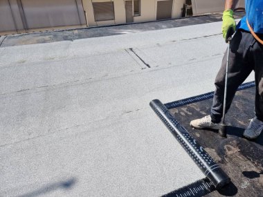 asfalt teras yalıtımlı su geçirmez kurulum bir binanın bakımında çalışıyor.