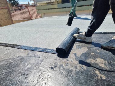 asfalt teras yalıtımlı su geçirmez kurulum bir binanın bakımında çalışıyor.