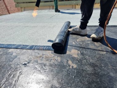 asfalt teras yalıtımlı su geçirmez kurulum bir binanın bakımında çalışıyor.