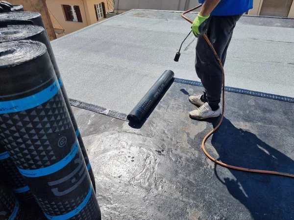 asfalt teras yalıtımlı su geçirmez kurulum bir binanın bakımında çalışıyor.