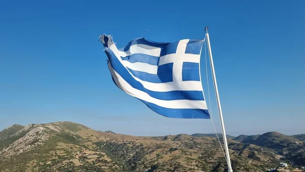 Yunan bayrağı, güneşli bir günde rüzgarda dalgalanıyor ve mavi gökyüzü Yunan adasında gökyüzünde