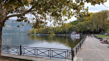 Sonbaharda ioannina ya da Giannena sesaon gölü ağaçları tekneler mavi gökyüzü yansımaları Yunanistan