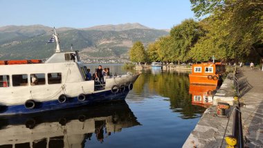 Sonbaharda ioannina ya da Giannena sesaon gölü ağaçları tekneler mavi gökyüzü yansımaları Yunanistan