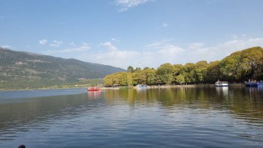 Sonbaharda ioannina ya da Giannena sesaon gölü ağaçları tekneler mavi gökyüzü yansımaları Yunanistan