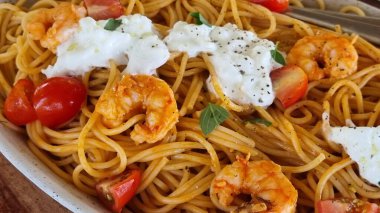 Domatesli karides spagetti ve bir tabakta yoğurt ve ahşap masa.