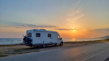 Deniz kenarındaki karavan, günbatımı renklerinde.