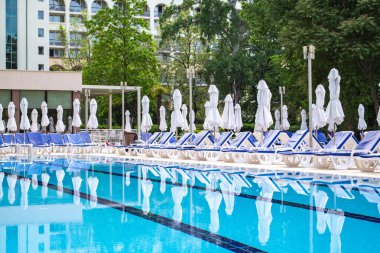 Swimming pool with empty loungers and closed umbrellas at luxury hotel . High quality photo