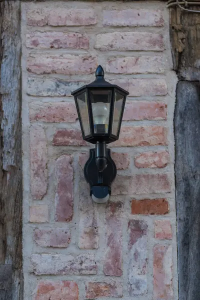 Kuzey Almanya 'da yarı keresteli tarihi bir evin ön cephesinde klasik bir fener. Kırmızı tuğla, tahta kirişler ve Alman kültür mirasını yansıtan otantik mimari ayrıntılar.