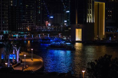Dubai Marina 'nın modern gökdelenleri ve şehir ışıkları akşam saatlerinde şehir mimarisi ve canlı gece yaşamını gözler önüne seriyor..