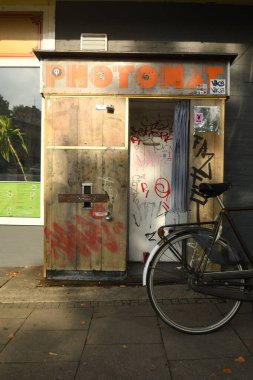 Vertical shot of a vintage style wooden Photo Booth with a bike parked in front of it. clipart