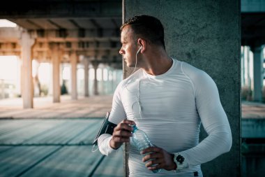 Sportsman drinking water from the plastic bottle after training.