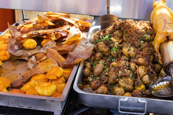 stock image Big metal dishes with potato balls, pig's skin, whole potatoes and roasted guinea pig (cuy) traditional delicious food of Latin America which serves in local restaurant of typical food. Cuenca,Ecuador