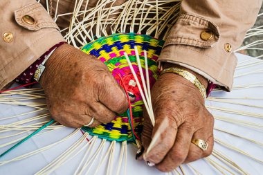 Paja Toquilla Straw 'dan bir paspas ören kadın ellerinin yakın çekimi. Saman el işi Ekvador 'dan popüler bir hediyedir..