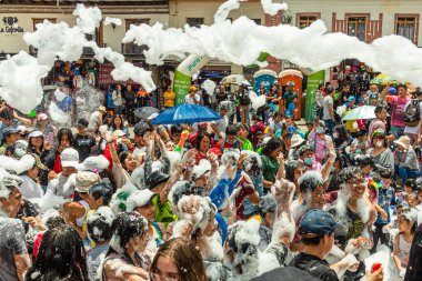 Cuenca, Ekvador - 18 Şubat 2023: Cuenca 'da Yıllık Karnaval Geçidi. Seyirci ve katılımcılar eğlenirken, insanlar itfaiye arabasından köpük püskürtüyor..