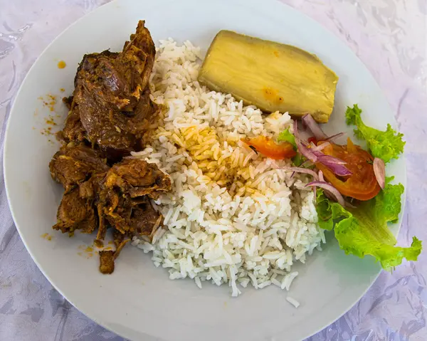 Exotic traditional dish from south of Ecuador (Mangahurco, Zapotillo): Chivo al hueco (goat al hollow) accompanied by rice, salad, sweet potato. Animal cooked whole in a pot on hot stones underground.