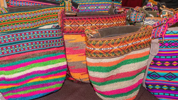 Crochet bags made of natural palm fiber with ornamental textile trims, handmade by artisans from Imbabura province of Ecuador. Open artisan market