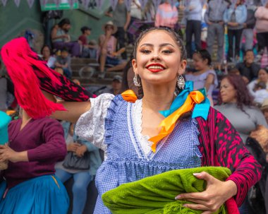 Cuenca, Ekvador - 1 Kasım 2023: Şehrin Bağımsızlık Günü 'nün kutlanması. Genç bir kadın, Azuay (Cuencana) şehrinin tipik kostüm giymiş folk dansçısı ve pazarda bir sepet satıcısı.