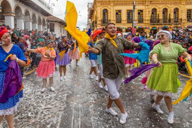 Cuenca, Ekvador - 10 Şubat 2024: Dansçılar Cuenca, Ekvador 'un tarihi merkezinde düzenlenen geleneksel Karnaval geçidinde gösteri yapıyorlar. Geleneksel olarak, köpük tören katılımcıları ve izleyiciler tarafından püskürtülür.