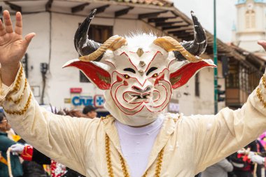 Cuenca, Ekvador - 10 Şubat 2024 Cuenca 'nın tarihi merkezinde karnaval geçidi. Beyaz şeytan maskeli bir adam. Geleneksel olarak, geçit töreni katılımcıları ve seyirciler köpük püskürtür.