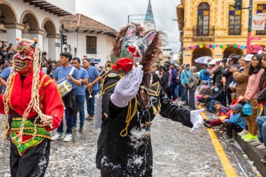 Cuenca, Ekvador - 10 Şubat 2024 Cuenca 'nın tarihi merkezinde karnaval geçidi. Korkunç yaratık maskeli bir insan gül sunar. Geleneksel olarak, geçit töreni katılımcıları ve seyirciler köpük püskürtür.