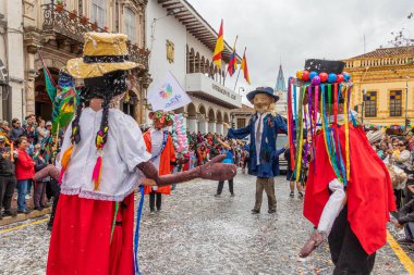 Cuenca, Ekvador - 10 Şubat 2024: Cuenca 'nın tarihi merkezinde düzenlenen yıllık karnaval geçidi sırasında bir geçit töreni. Geleneksel kostümlü dev mankenler ve diğerleri. Katılımcıların üzerine köpük püskürtülür