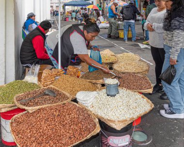 Cuenca, Ekvador - 29 Mart 2024: Kimliği belirlenemeyen kadın markette yemek pişirmek için kullanılan malzemeleri satıyor. Çeşitli tahıllar, baklagiller, sebzeler. Kutsal hafta ve Paskalya 'da yenen Ekvador yemekleri