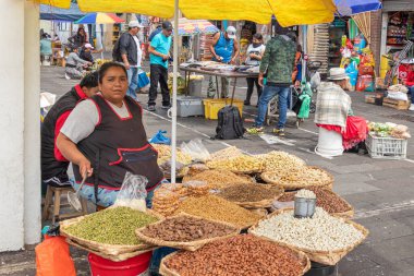 Cuenca, Ekvador - 29 Mart 2024: Kimliği belirlenemeyen kadın markette yemek pişirmek için kullanılan malzemeleri satıyor. Çeşitli tahıllar, baklagiller, sebzeler. Kutsal hafta ve Paskalya 'da yenen Ekvador yemekleri