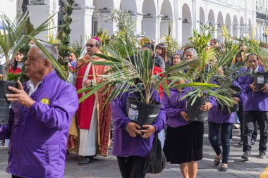 Cuenca, Ekvador - 24 Mart 2024: Kutsal Hafta. Kimliği belirlenemeyen insanlar ve bir rahip, Palm Sunday 'in Katolik kutlaması sırasında el ele tutuşup geçit törenine katılıyorlar.