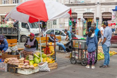 Cuenca, Ekvador - 29 Mart 2024: Cuenca 'da gıda pazarı' 9 de Octubre '. Bir kadın satıcı pazar binasının yanında sebze satıyor. Ekvador
