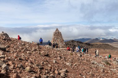 Chimborazo, Ekvador - 20 Nisan 2025: Chimborazo Volcano, And Dağları. Carrel sığınağındaki bir grup turist deniz seviyesinden 4,845 metre yükseklikte taş piramidin yanında kardinal istikametini gösteriyor.
