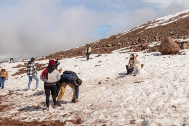 Chimborazo, Ekvador - 20 Nisan 2025: Karla kaplı Chimborazo volkanı, Chimborazo rezervi, And Dağları. Bir grup turist kartopu oynuyor ve volkanın yamacında fotoğraf çekiyor.