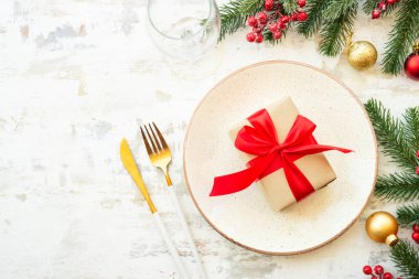Tabak, hediye, altın çatal bıçak, cam ve Noel süslemeleri beyaz ahşap arka planda. Kopyalama alanı olan üst görünüm.
