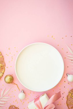 Beyaz tabak, çatal bıçak takımı ve pembe arka planda noel süslemeleri olan bir Noel masası. Kopyalama alanı olan düz resim.