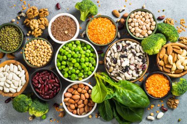 Vegan protein kaynağı. Baklagil, fasulye, mercimek, fındık, brokoli, ıspanak ve tohum. Taş masadaki en üst manzara. Sağlıklı vejetaryen yemekleri.